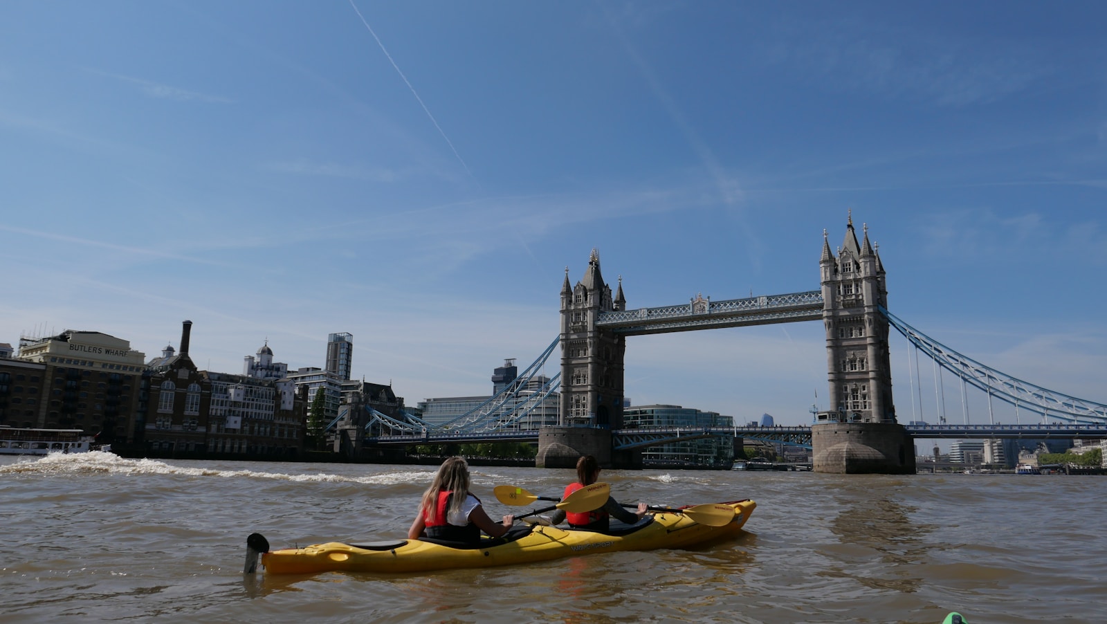 Two people in a kayak in front of Tower Bridge