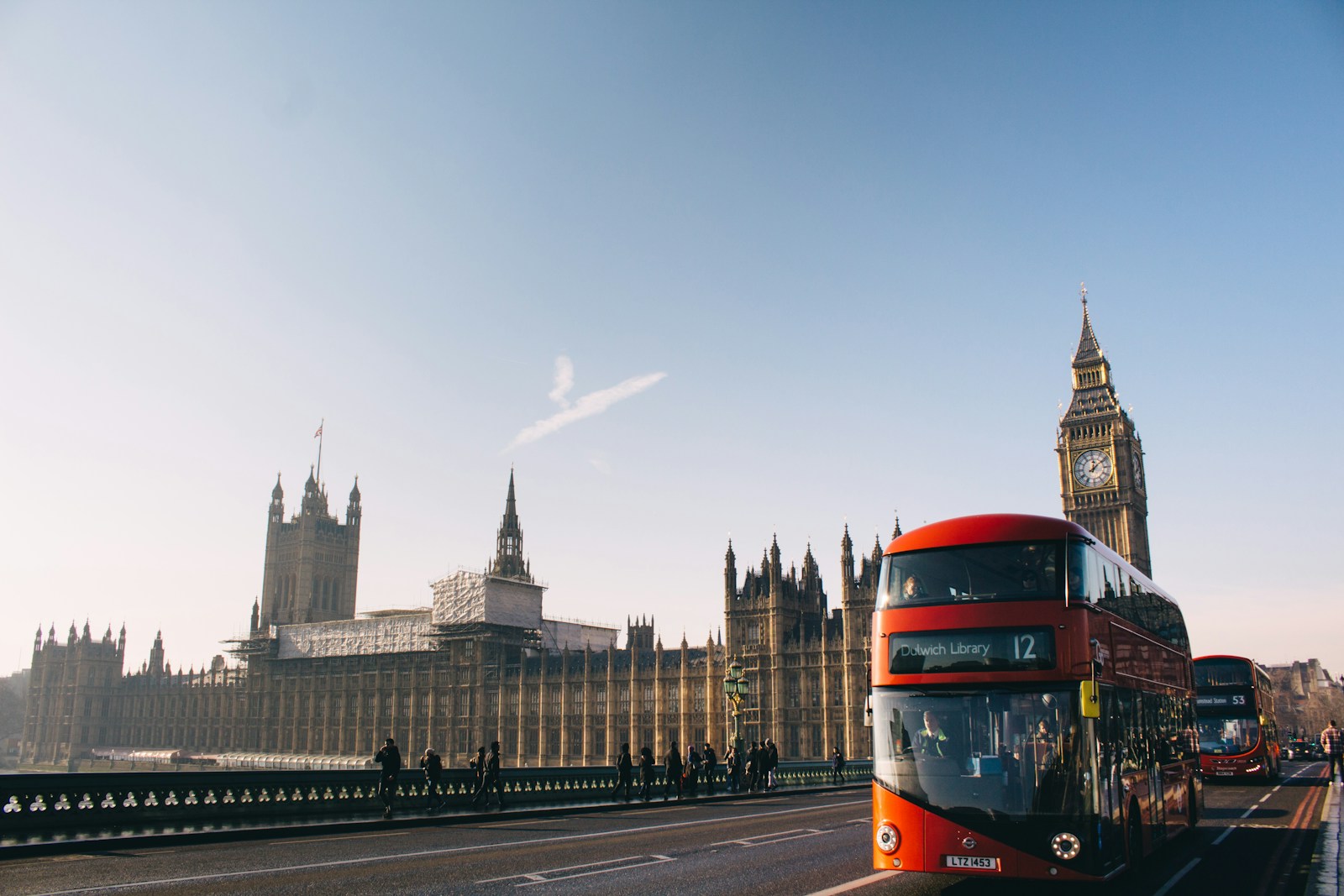 Red double-decker bus passing Palace of Westminster in London