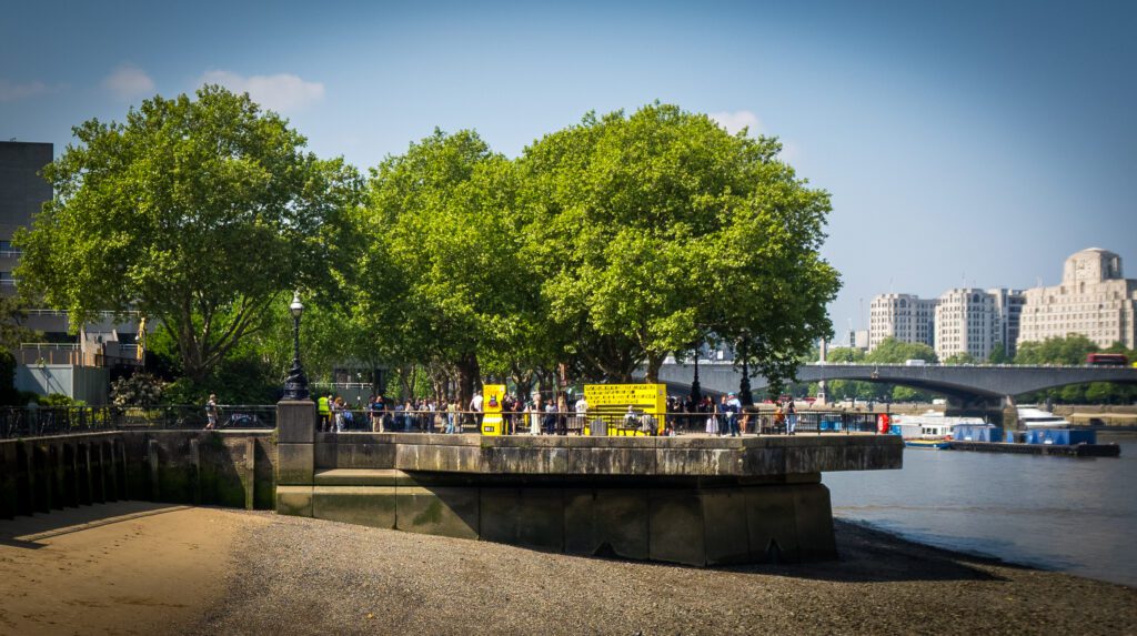 Beach on the River Thames at low tide with the tree-lined walkway beyond the beach