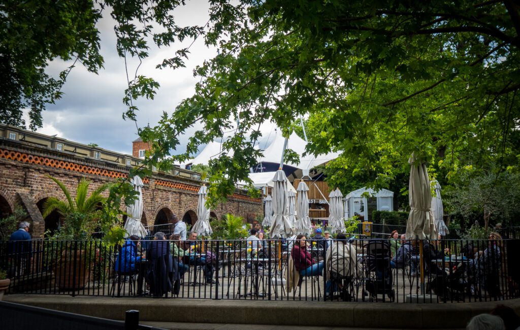 People sitting at tables and chairs outside a cafe
