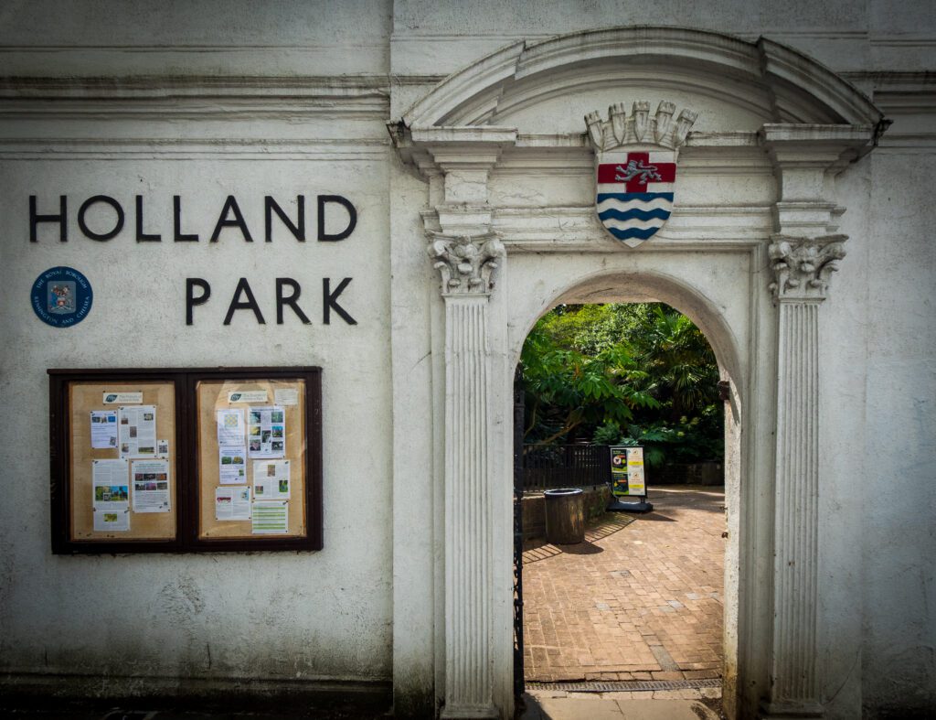 An arched entrance in a stone wall into Holland Park