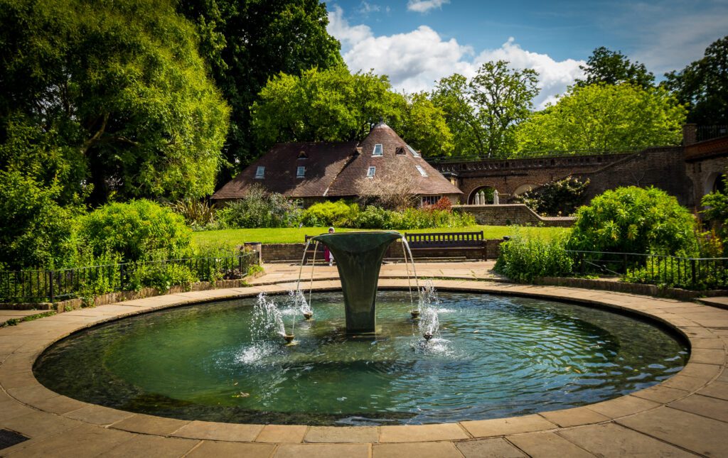 Circular pond with fountain in the middle with gardens behind