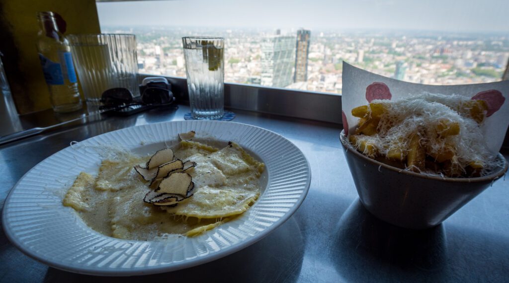 Truffle ravioli with parmesan fries on a bar table looking at a view of London
