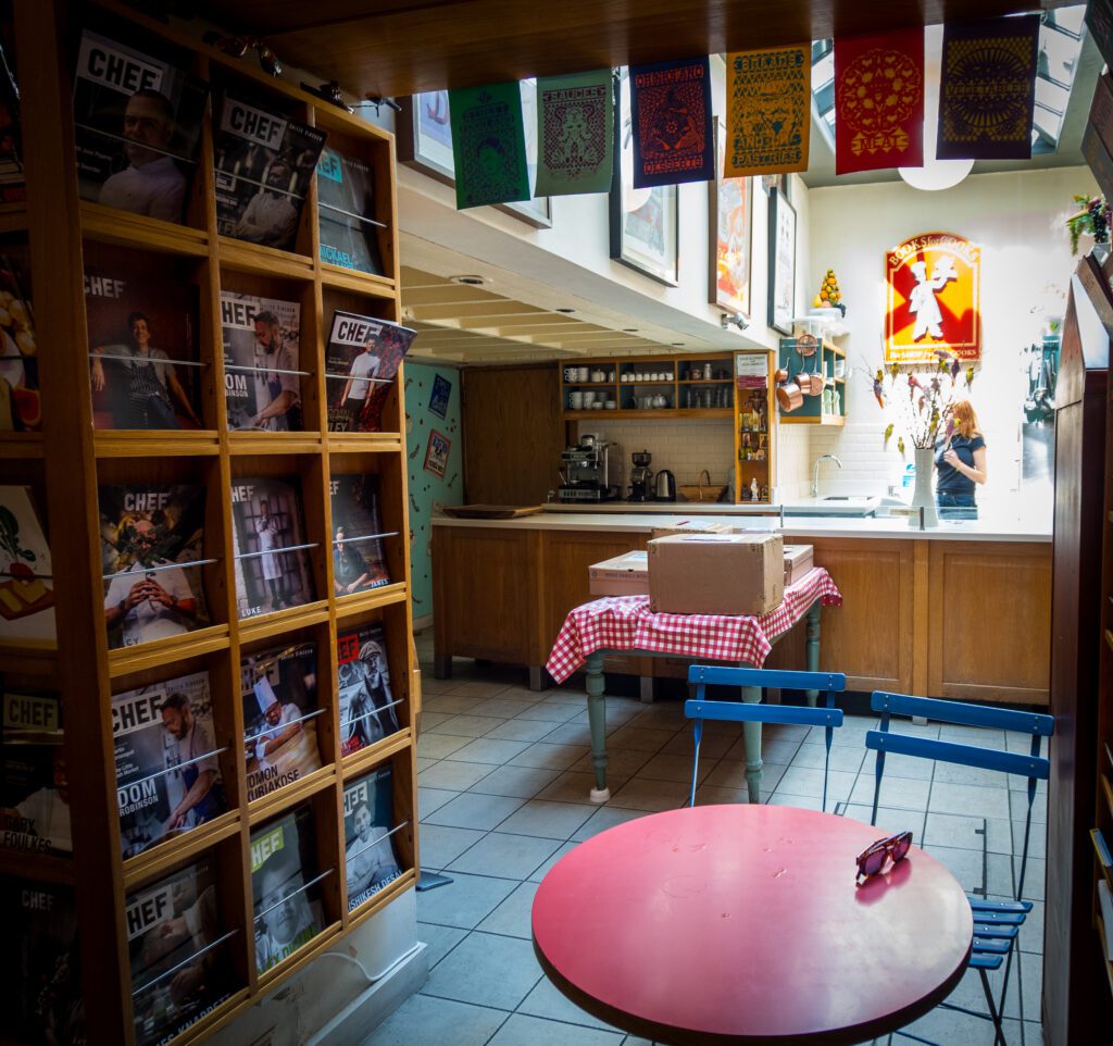 Cafe table and kitchen area behind the book shelves
