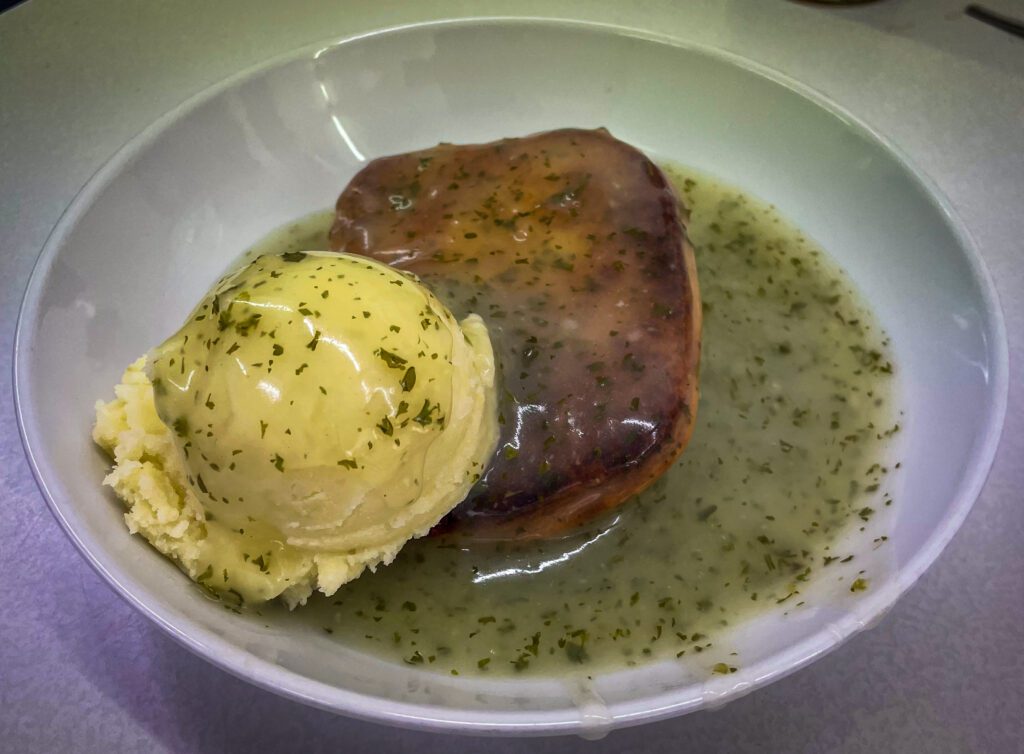 Beef mince pie and mash with Parsley liquor in a white bowl
