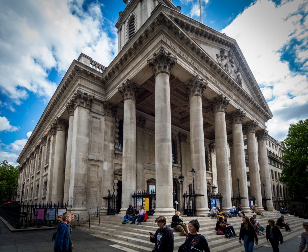Tall, imposing columns outside St. Martin in the Fields with people sitting on the steps underneath