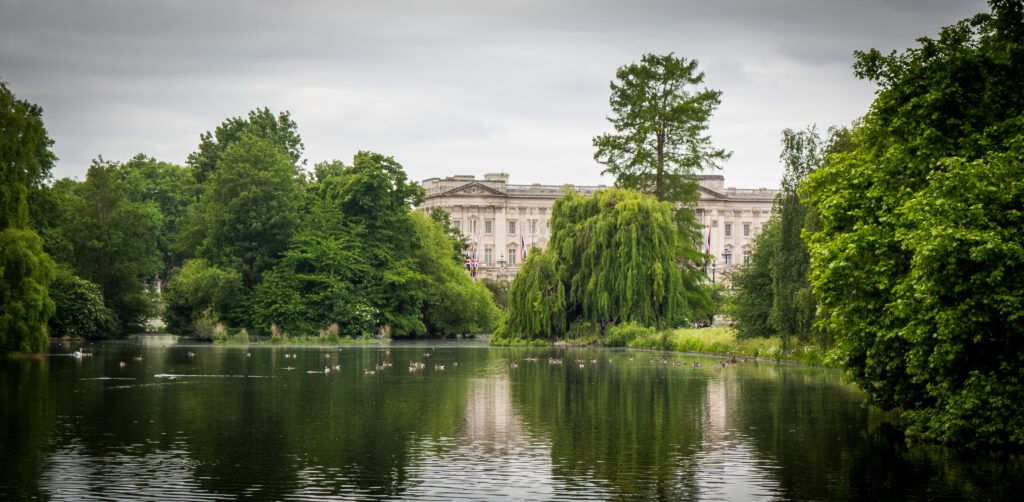 A view of Buckingham Palace with a lake and trees in front of the palace