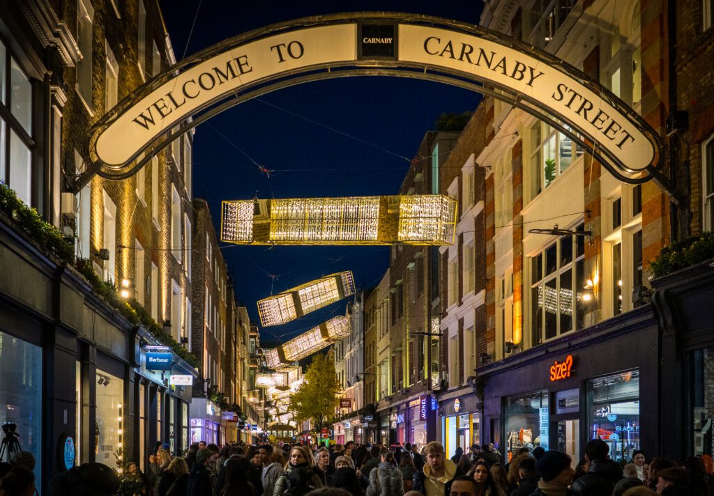 Pedestrians walking down Carnaby Street with Christmas Decorations hanging above them