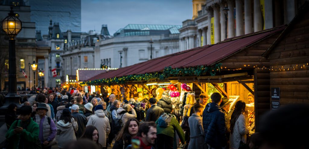 People walking next to the Christmas Market stalls at Trafalgar Square