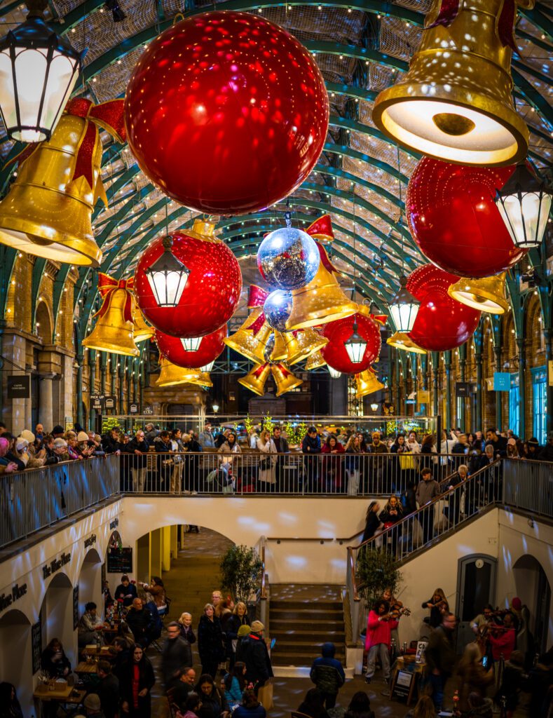 Baubles and Bells Christmas decorations hanging from the ceiling inside the market at Covent Garden