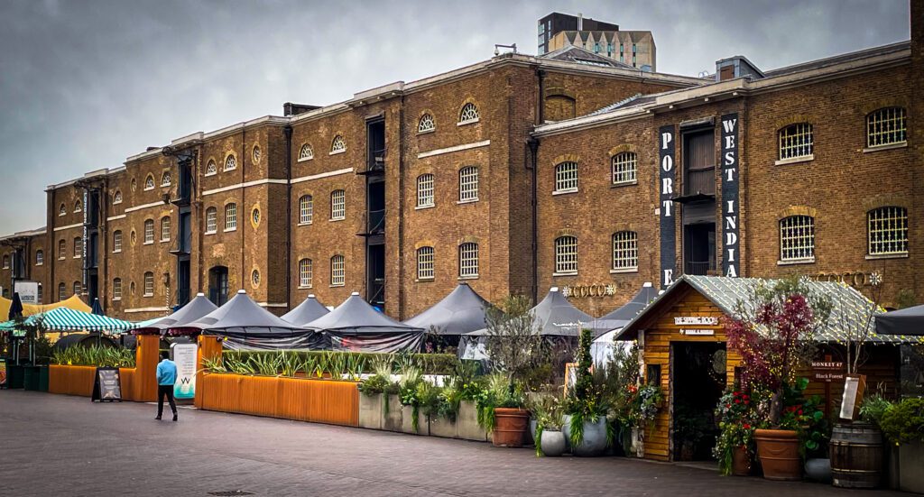 A row of restaurants with outdoor seating under cover. They are based on the ground floor of a row of original warehouse buildings in Canary Wharf