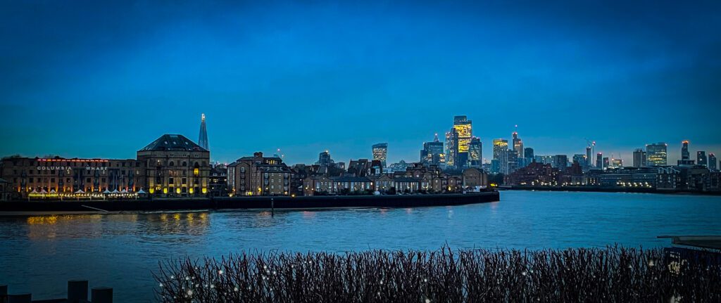 River Thames with buildings lining the side with the high rise buildings of central London in the distance