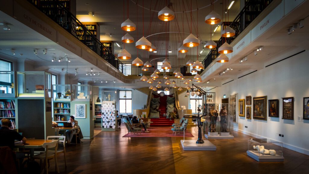 Bookshelves and tables on the outskirts of The Reading Room with comfy chairs in the middle