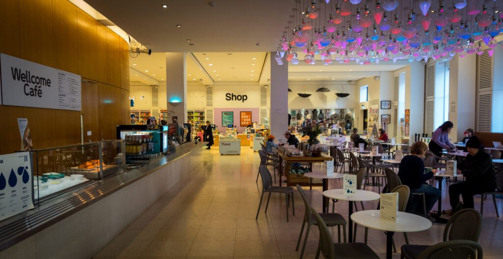 Cafe with tables and chairs. Counter to order to food with the museum shop at the back.